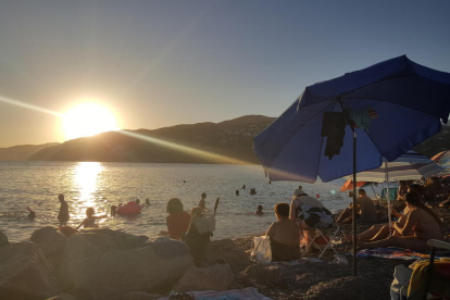 El sol s'amaga darrere les muntanyes mentre els  banyistes gaudeixen a la platja de Salobreña a la  costa tropical de Granada.