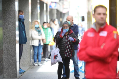 Moltes persones esperen al carrer amb la mascareta posada