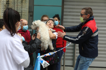 El director adjunt de bombers, Jordi Farré, entrega el gos rescatat d'un pis als propietaris