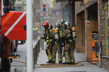 Els bombers a la porta de la botiga amb el fum sortint de l'establiment