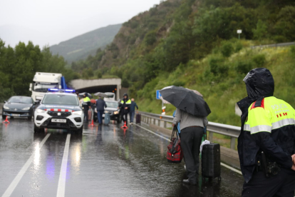 Viatgers d'Andbus sota la pluja per passar el bloqueig