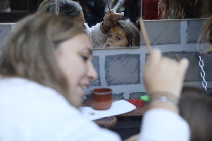 Una nena mirant-se al mirall mentre està sent pintada al taller de pintura facial