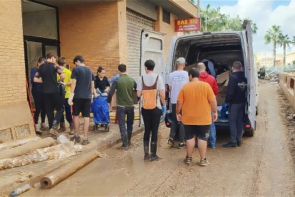 Veïns fent una cadena humana per descarregar productes de la furgoneta, a Benetússer.