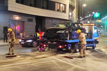 Els bombers fent tasques de neteja al lloc de l'accident mentre la grua s'emporta el vehicle