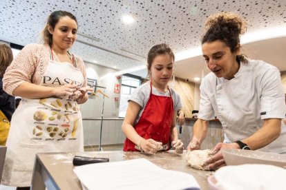 L'especialista Núria Robert ensenyant a fer pa a dues alumnes del taller.