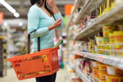 Una dona amb productes d’alimentació a la cistella.