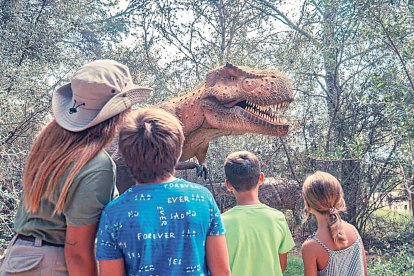 Un grup de nens contempla un tiranosaure rex a Dinosaurland.
