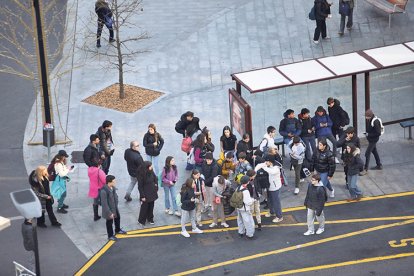 Estudiants en una parada de bus a la capital.