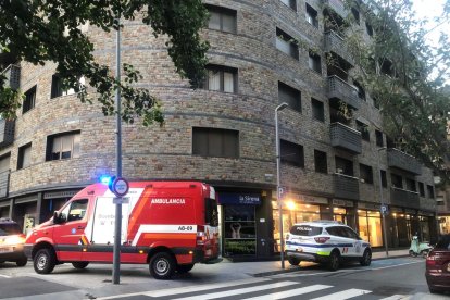 L'ambulància dels bombers i un vehicle de policia davant l'edifici on es troba el pis de la persona afectada.
