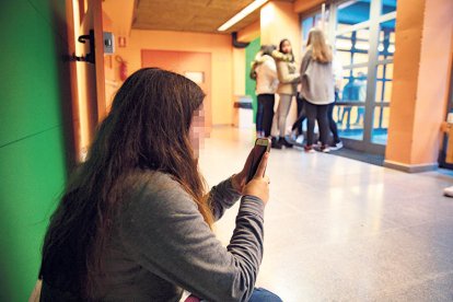 Una estudiant amb un telèfon mòbil.