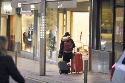 Una dona carrega dues maletes a la part alta d’Escaldes.
