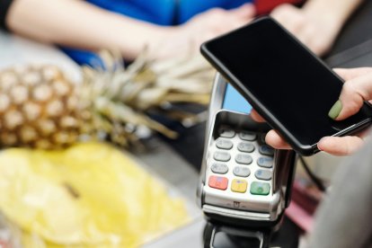 Una noia paga una compra amb el mòbil.