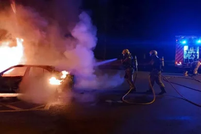 Bombers intervenint amb el cotxe incendiat.