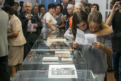 Diverses persones en una exposició sobre la col·lecció de bíblies del Santuari Meritxell d'Andorra.