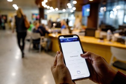 Una persona utilitzant un telèfon intel·ligent a l’edifici del Govern.