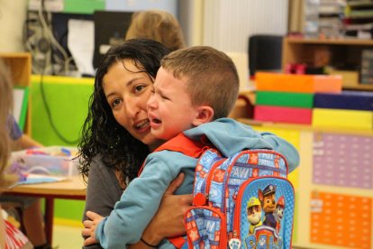 Una mestra abraçant un nen petit