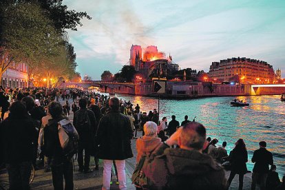 Desenes de persones observen vora el Sena la columna de fum i les flames