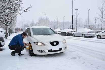 Un conductor posant les cadenes al seu vehicle a la Seu