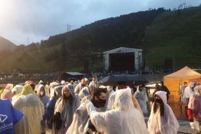 Assistents al concert protegits contra la pluja que va retardar l'actuació més d'una hora.