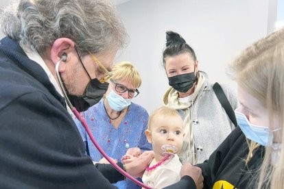 El metge visitant el nen d'un any, acompanyat de la mare, ahir.