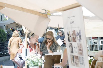 Dues dones es miren amb interès els productes d'una de les parades del mercat de la Vall.