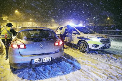 Un vehicle amb matrícula espanyola i un de la policia en un moment de la nevada.