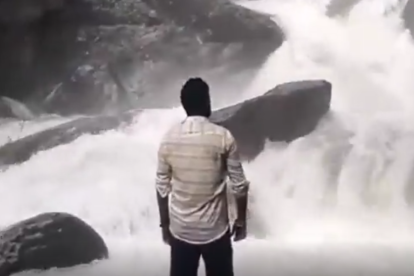 Un home rellisca mirant una cascada