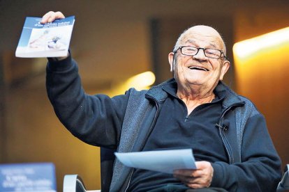 Mossèn Ramon somrient amb el llibre a la mà.