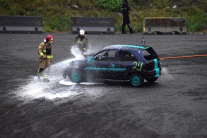 Els bombers ruixant el motor d’un cotxe.