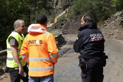 Un operari, un treballador de l'empresa de maquinaria i un mosso d'esquadra observant l'esllavissada.