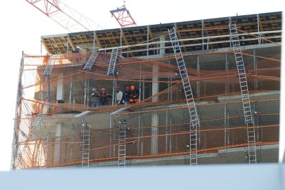 Diversos operaris a la bastida de la part superior de l'edifici on s'ha produït el desprendiment