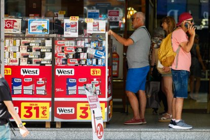 Uns turistes mirant els preus del tabac.