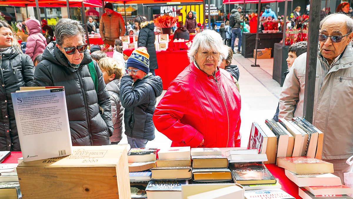 Diferents persones observant els llibres exposats d’una parada d’aquest Sant Jordi.