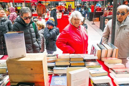 Diferents persones observant els llibres exposats d’una parada d’aquest Sant Jordi.