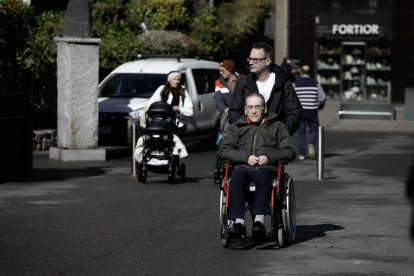 Una persona en cadira de rodes passejant per la capital.