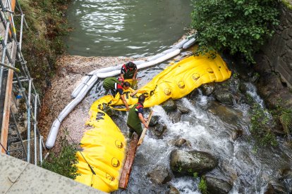 Equips de neteja treballant al riu Madriu per controlar el vessament.