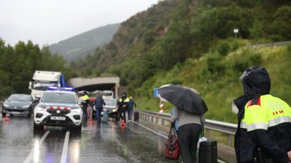 Viatgers d'Andbus sota la pluja per passar el bloqueig