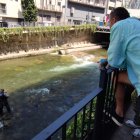 Uns turistes contemplant un parell de pescadors a la capital, ahir.