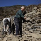 Treballadors durant la reparació d’un mur fet amb la tècnica de la pedra seca.