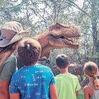 Un grup de nens contempla un tiranosaure rex a Dinosaurland.