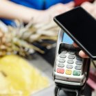 Una noia paga una compra amb el mòbil.