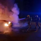 Bombers intervenint amb el cotxe incendiat.