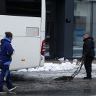 Dues persones posant cadenes a un autocar.