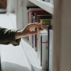 Un estudiant seleccionant un llibre en una biblioteca.