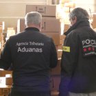Un agent dels mossos d'esquadra i un altre de duanes de Catalunya, amb la mercaderia interceptada.