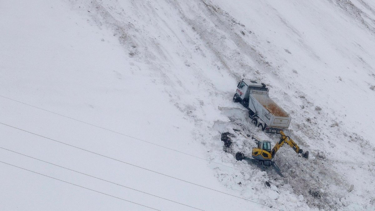 La màquina excavadora treballant per retirar la neu que envolta el camió caigut al Pas.