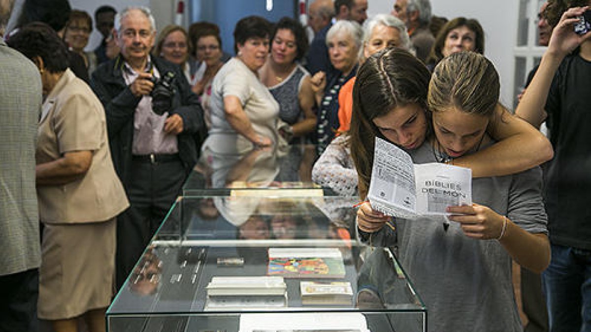 Diverses persones en una exposició sobre la col·lecció de bíblies del Santuari Meritxell d'Andorra.