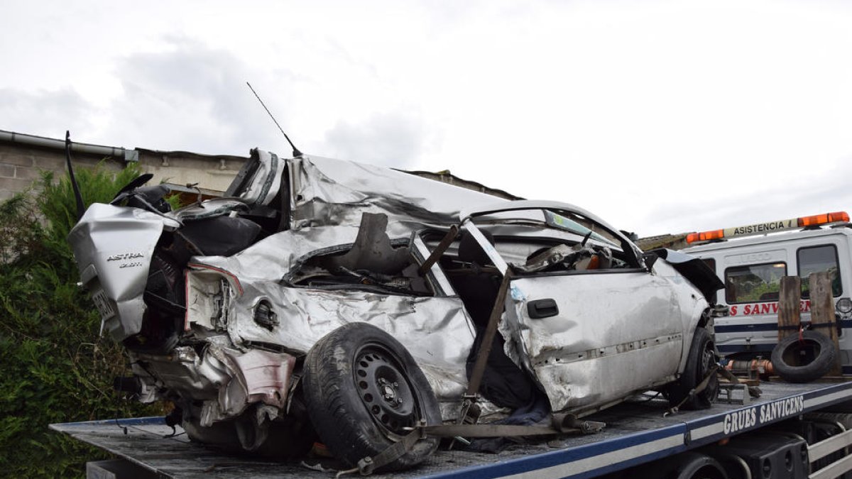 El turisme accidentat enfilat damunt la grua.