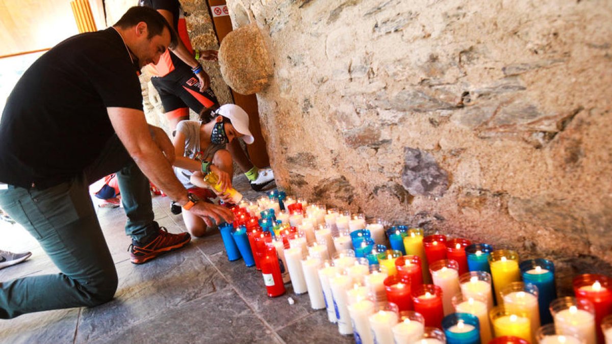 Un pare i la filla encenent un ciri davant l'antiga església.