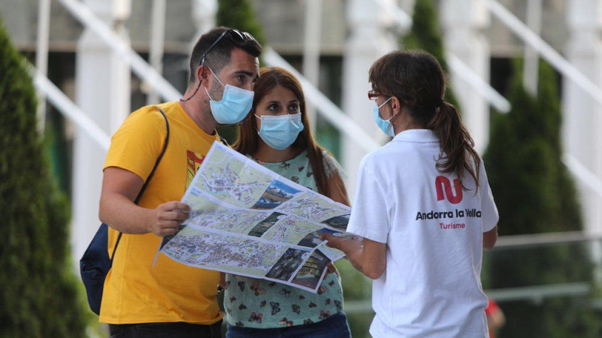 Una tècnica de turisme d'Andorra la Vella informa dos visitants.